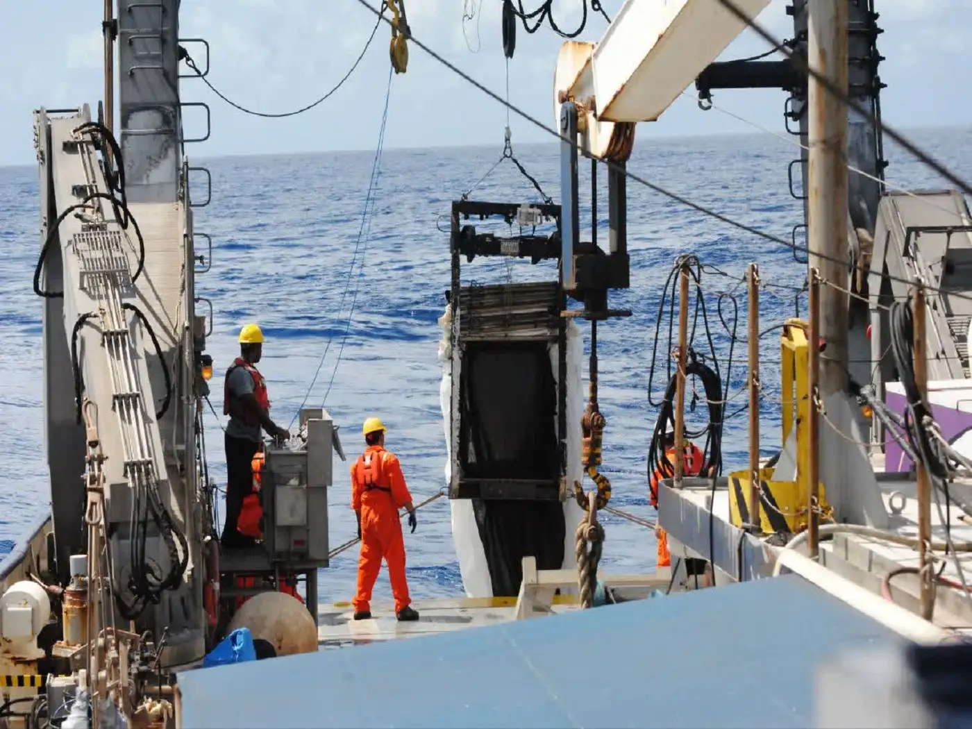 Marine professionals handling technical equipment aboard a vessel during work relevant to marine engineering research reviews